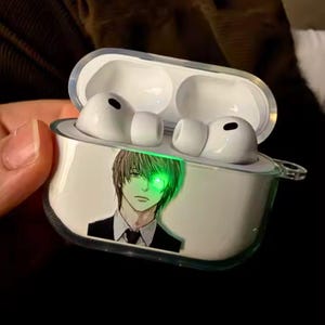 May include: White wireless earbuds in a clear case featuring an anime character illustration with a glowing green eye. The case is open, showing the earbuds within.