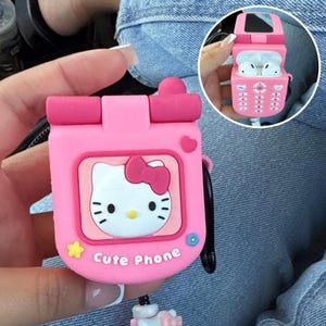Puede incluir: Funda rosa de silicona para AirPods con forma de teléfono móvil retro, con diseño de Hello Kitty. La funda tiene un diseño abatible y las palabras "Cute Phone" están impresas en la parte delantera. Se adjunta un cordón negro.