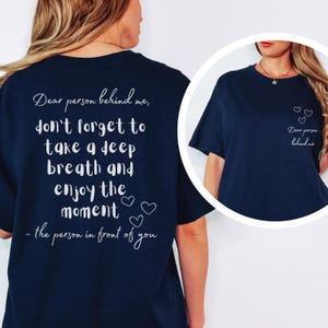 Op de afbeelding: Marineblauw T-shirt met witte tekst: "Beste persoon achter me, vergeet niet diep adem te halen en van het moment te genieten - de persoon voor je." Met drie kleine hartjes.