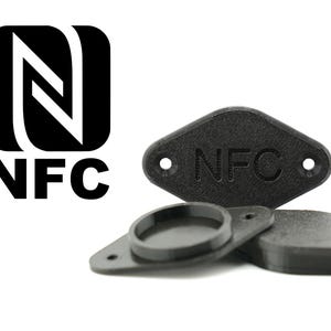 Könnte beinhalten: Schwarze NFC-Tags mit dem NFC-Logo und dem Aufdruck „NFC“. Die Tags sind klein, rechteckig und haben abgerundete Kanten mit zwei Löchern. Das Logo ist schwarz und weiß.
