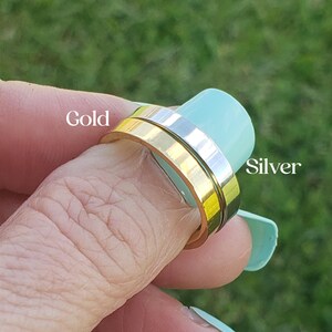 Puede incluir: Un anillo de oro y plata con un dise&ntilde;o giratorio. El anillo se lleva en un dedo.