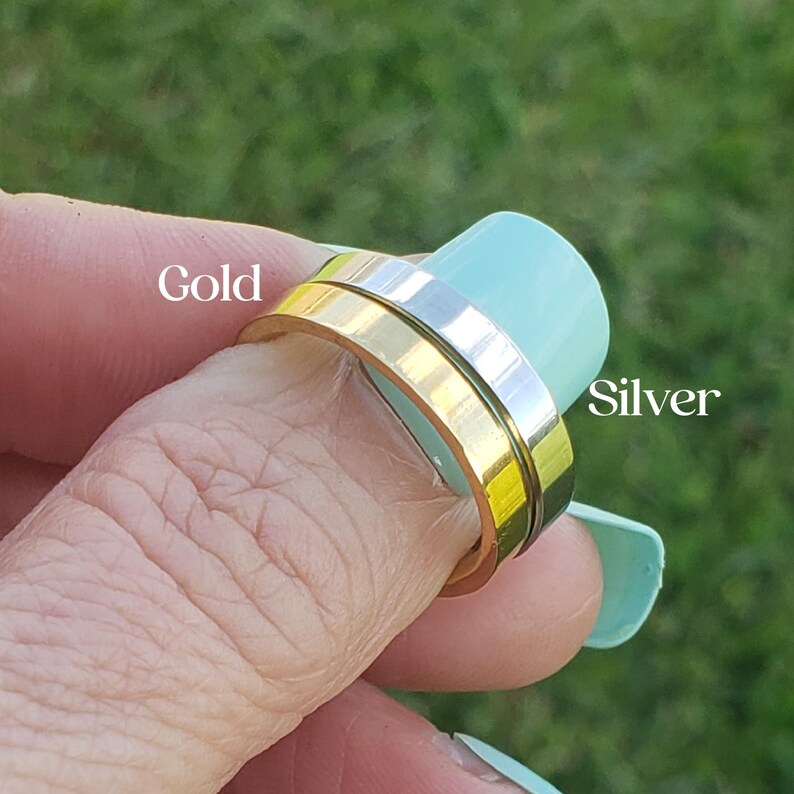 Puede incluir: Un anillo de oro y plata con un dise&ntilde;o giratorio. El anillo se lleva en un dedo.