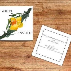Könnte beinhalten: Zwei weiße Einladungskarten auf einer Holzoberfläche. Eine Karte hat den Text "YOU'RE INVITED" mit einer Zitronen- und Orangenillustration. Die andere Karte enthält Details für einen Verlobungsbrunch.