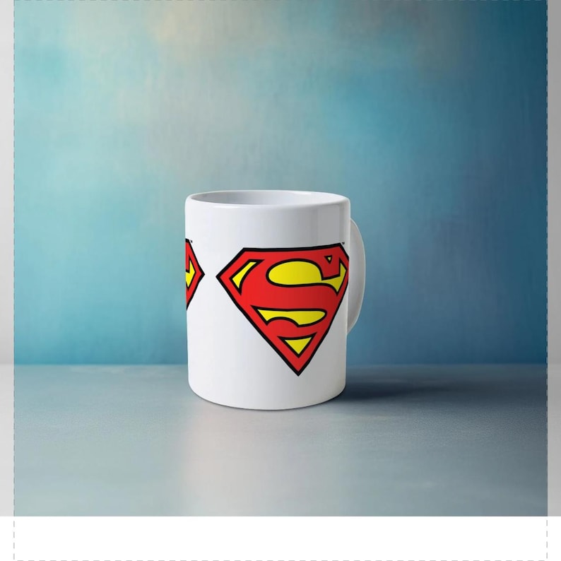 May include: White ceramic mug featuring the Superman logo in red, yellow, and black. The iconic "S" shield is prominently displayed on the mug's surface. The mug has a curved handle and a cylindrical shape.