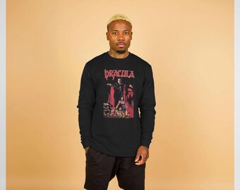 May include: Black long-sleeve sweatshirt featuring a graphic of Dracula in red and black. The word "DRACULA" is printed in red across the top. The sweatshirt is worn by a person.