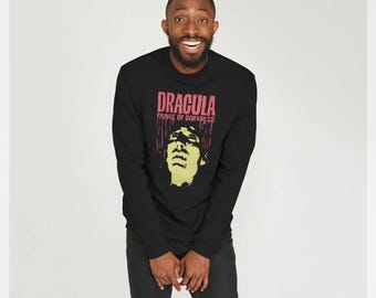 Könnte beinhalten: Schwarzes Langarm-Sweatshirt mit dem Text "DRACULA PRINCE OF DARKNESS" in Rosa und einer gelb-grünen Grafik eines Männergesichts. Das Sweatshirt wird von einer Person getragen.