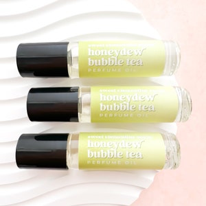 May include: Three glass roller bottles with black caps and yellow labels. The labels read "sweet clementine soaps honeydew bubble tea PERFUME OIL".
