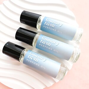 May include: Three glass roller bottles with blue and white labels that say "laundry fresh perfume oil" and "sweet clementine mango".