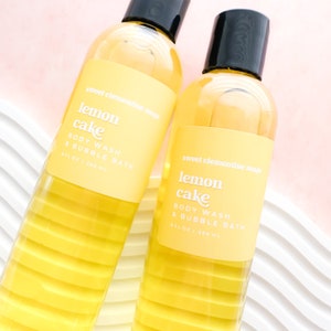 May include: Two clear yellow bottles of sweet clementine soap with a lemon cake scent. The bottles are labeled "sweet clementine soap lemon cake body wash & bubble bath 8 fl oz | 266 mL"
