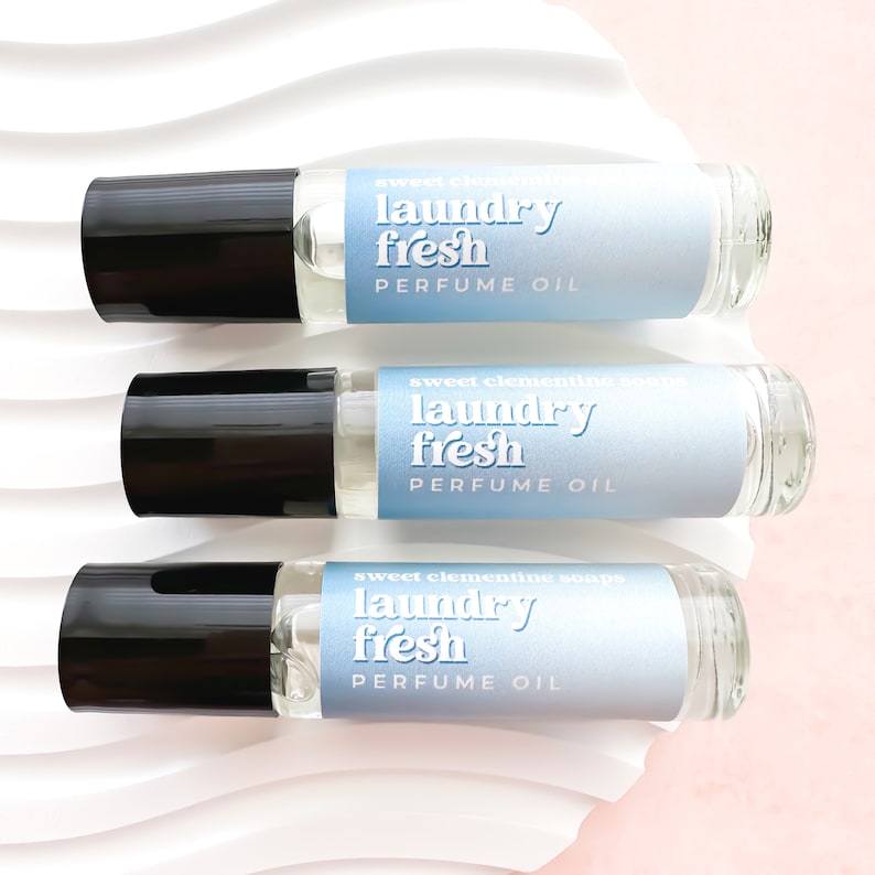 May include: Three glass roller bottles with black caps and blue labels. The labels read "sweet clementine soaps laundry fresh perfume oil".