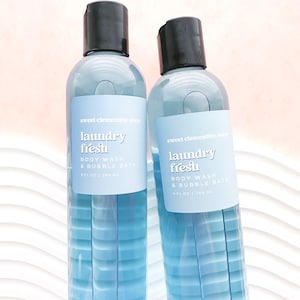 May include: Two clear plastic bottles of sweet clementine soap body wash and bubble bath. The bottles are labeled "laundry fresh" and are 9 fl oz / 268 ml.