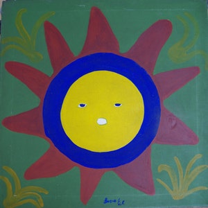 May include: A red sun with a yellow face and blue eyes, painted on a green background with yellow grass.