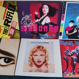 May include: A collection of eight vintage vinyl records, including albums by Madonna, Iron Maiden, and Urban D'orban. The records feature a variety of genres, including pop, rock, and dance music.