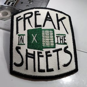 May include: Embroidered patch with the words "FREAK IN THE SHEETS" in black thread on a white background. The patch has a black border and a green graphic in the center.
