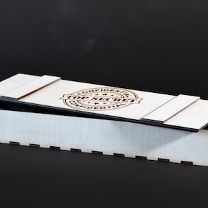 May include: White wooden box with a black lid. The lid has a brown stamp that says "CONFIDENTIAL TOP SECRET CONFIDENTIAL".