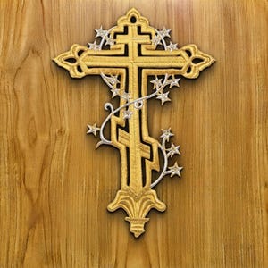 Puede incluir: Un parche bordado en forma de cruz dorada con un diseño intrincado de varias barras. La cruz está adornada con un elemento de vid en tono plateado que se envuelve alrededor de la estructura, decorado con varias estrellas pequeñas de cinco puntas.