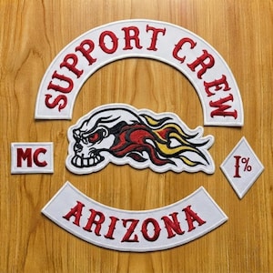 May include: A set of embroidered patches featuring a white arched top rocker with red text reading SUPPORT CREW, a white bottom rocker with red text reading ARIZONA, a rectangular MC patch, a diamond 1% patch, and a central skull graphic.
