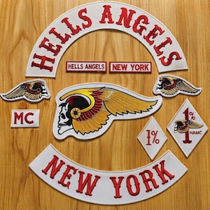 May include: A collection of embroidered patches including a large arched HELLS ANGELS top rocker, a NEW YORK bottom rocker, a central winged skull emblem, two smaller winged skull patches, an MC patch, and two diamond-shaped 1% patches.