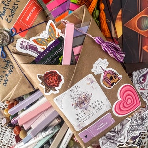 May include: A brown paper package with a variety of items, including a book, a tea bag, and a sticker that says "Blind Date with a Book". The package is decorated with a variety of stickers, including a butterfly, a flower, and a heart.