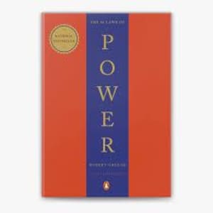 Może przedstawiać: Czerwona książka w twardej oprawie z niebieskim grzbietem. Tytuł "The 48 Laws of Power" jest nadrukowany złotymi literami na grzbiecie. Imię autora, "Robert Greene", jest nadrukowane mniejszymi złotymi literami pod tytułem.