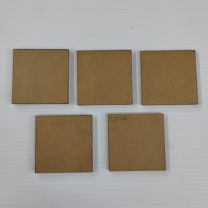 May include: Five square, unfinished wooden coasters. One coaster has the dimensions "2.5 x 2.5" written on it. The coasters are a light brown color and are arranged on a white surface.