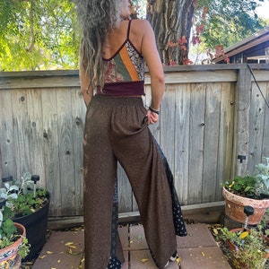 May include: Brown wide-leg pants with a black and white patterned trim. The pants have a high waist and a loose fit.