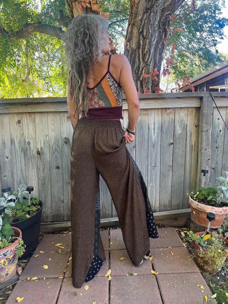 May include: Brown wide-leg pants with a black and white patterned trim. The pants have a high waist and a loose fit.