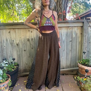 May include: Brown wide-leg pants with a geometric pattern on the sides. The pants are made of a soft, flowing fabric and have a high waist.