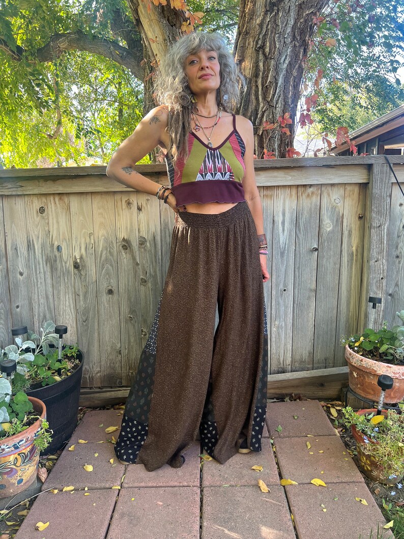 May include: Brown wide-leg pants with a geometric pattern on the sides. The pants are made of a soft, flowing fabric and have a high waist.