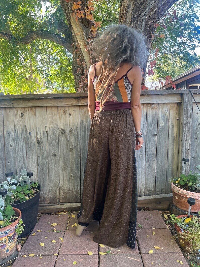 May include: Brown wide-leg pants with a black and white patterned side panel. The pants are made of a soft, flowing fabric and have a relaxed fit.