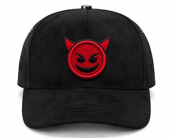 May include: A black baseball cap featuring a centered embroidered patch of a red circular devil face with black eyes and a wide grin. The cap has a structured crown, a curved brim, and a small metallic button at the top center of the crown.