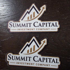 May include: Two stickers with the text "SUMMIT CAPITAL INVESTMENT COMPANY". The logo features a mountain design with a rising arrow, and three vertical bars. The stickers have a white background with a gold and black design.