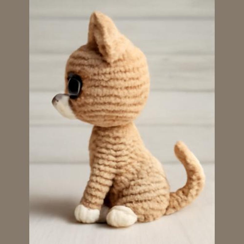 May include: A crocheted plush toy cat in a beige color with large eyes. The cat is sitting with its tail curled around its body.