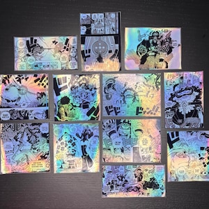 May include: A set of 12 holographic stickers featuring characters and scenes from the popular anime series One Piece. The stickers are printed on a clear, iridescent material and feature a variety of colors, including black, white, red, blue, and yellow. The stickers are perfect for adding a touch of anime flair to laptops, water bottles, notebooks, and more.