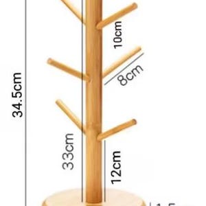 May include: A wooden mug tree with six hooks for hanging mugs. The tree is 12 inches tall, 1.5 inches wide, and 15.5 inches in diameter. The base is 2.5 inches tall.