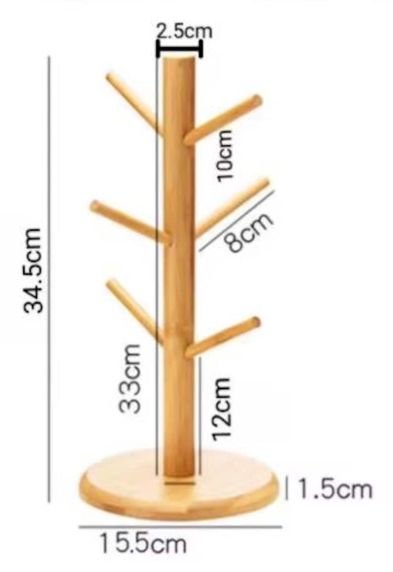 May include: A wooden mug tree with six hooks for hanging mugs. The tree is 12 inches tall, 1.5 inches wide, and 15.5 inches in diameter. The base is 2.5 inches tall.
