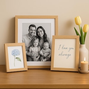 Peut inclure: Trois cadres photo en bois sur une surface en bois. Le plus grand cadre contient une photo en noir et blanc d'une famille de quatre personnes. Le cadre du milieu contient une photo en noir et blanc d'une fleur. Le plus petit cadre contient le texte "I love you always".