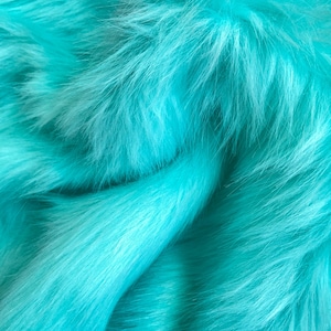 May include: Close-up of a soft, turquoise faux fur fabric. The fur is fluffy and has a smooth texture.