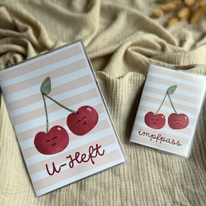 Puede incluir: Dos portapasaportes con diseño de cerezas. Los portadores tienen un fondo a rayas rosas y blancas. Uno tiene el texto "U-Heft" y el otro "impfpass". Las cerezas son rojas con tallos verdes.