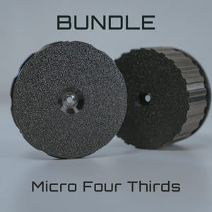 May include: Two dark grey, circular objects with textured surfaces, labelled "BUNDLE" and "Micro Four Thirds." One object has a ridged edge. The objects are on a white surface.