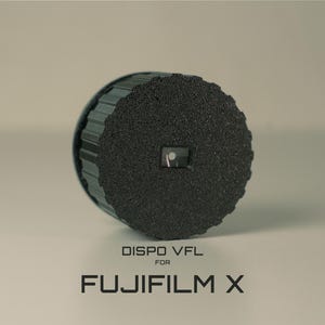 May include: A black camera accessory with a textured surface and a small, square opening. The text "DISPO VFL FOR FUJIFILM X" is printed below the accessory. The item appears to be a lens cap or a similar protective device.