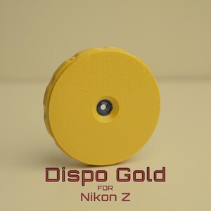 May include: A yellow Dispo Gold camera accessory for Nikon Z cameras. The accessory is circular with a textured surface and a small, dark blue centre. The text "Dispo Gold for Nikon Z" is displayed in red.