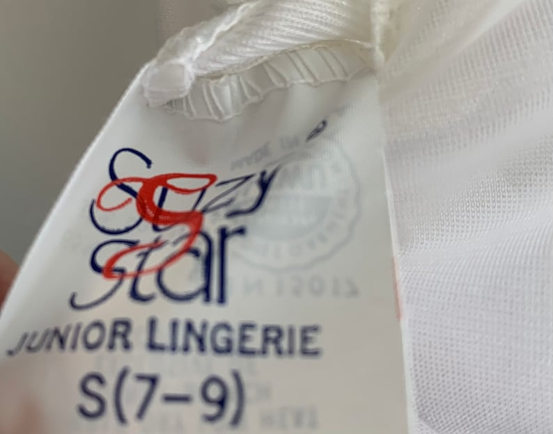 Puede incluir: Etiqueta blanca con texto azul y rojo que dice "Sizzy Star Junior Lingerie S(7-9)"