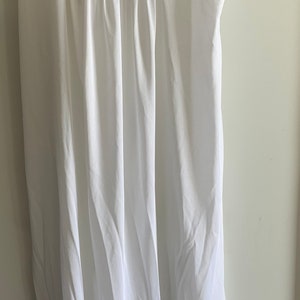 Puede incluir: Un camis&oacute;n blanco de algod&oacute;n con delicado encaje y bordado floral rosa. Las tiras son finas y ajustables.