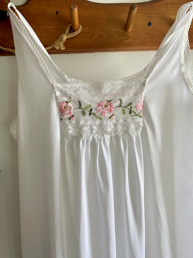 Puede incluir: Camis&oacute;n blanco de algod&oacute;n con delicado encaje y flores rosas bordadas.