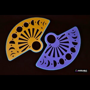May include: Two half-circle shaped stencils, one yellow and one purple, with a sun and moon design. The stencils are made of plastic and have a smooth, glossy finish.