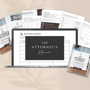 May include: A laptop displays a calendar layout with the text "THE ATTORNEY'S Planner." Several printed pages and two planner books surround the laptop. The books and pages have the same branding. The background is a neutral beige.