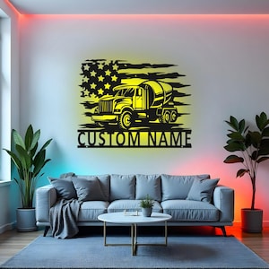May include: Black metal wall art featuring a cement mixer truck silhouette against a yellow and black American flag design. The text "CUSTOM NAME" is below the truck. This decorative piece is suitable for a home or office.