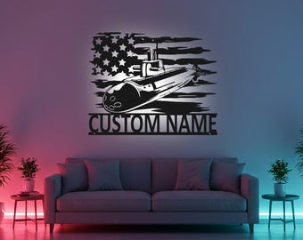 Puede incluir: Arte mural de metal negro con un diseño de submarino sobre una bandera estadounidense estilizada. El texto "CUSTOM NAME" se muestra debajo. La obra de arte está montada en una pared sobre un sofá gris.