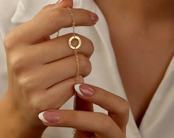 May include: A gold chain necklace with a circular pendant. The pendant has the words "Love" and "Life" engraved on it.